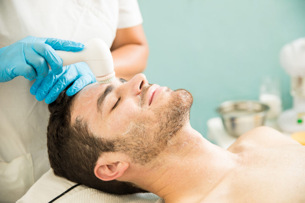 Happy male patient receiving facial exfoliation treatment — men's aesthetic clinics that invest in SEO see measurable growth in male patient consultations