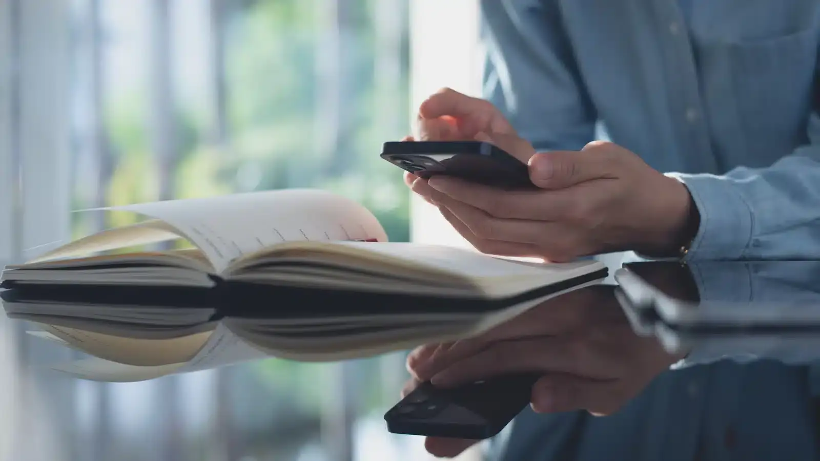Hands using a smartphone above a notebook, representing a patient completing a mobile booking where most aesthetic clinic conversions happen or are lost.