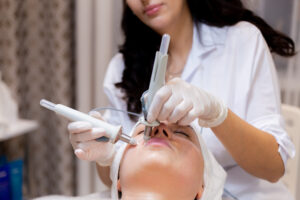 A young beautiful girl lies on the beautician's table and receives procedures with a professional apparatus for skin rejuvenation and moisturizing