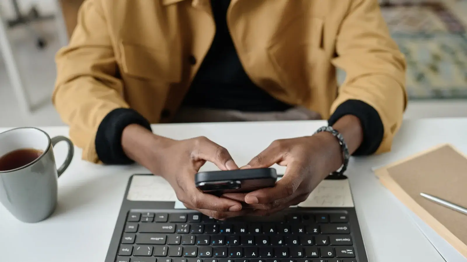 Hands typing a reply on a phone at a desk, illustrating how to write a HIPAA-safe response to a patient review without confirming a treatment relationship.