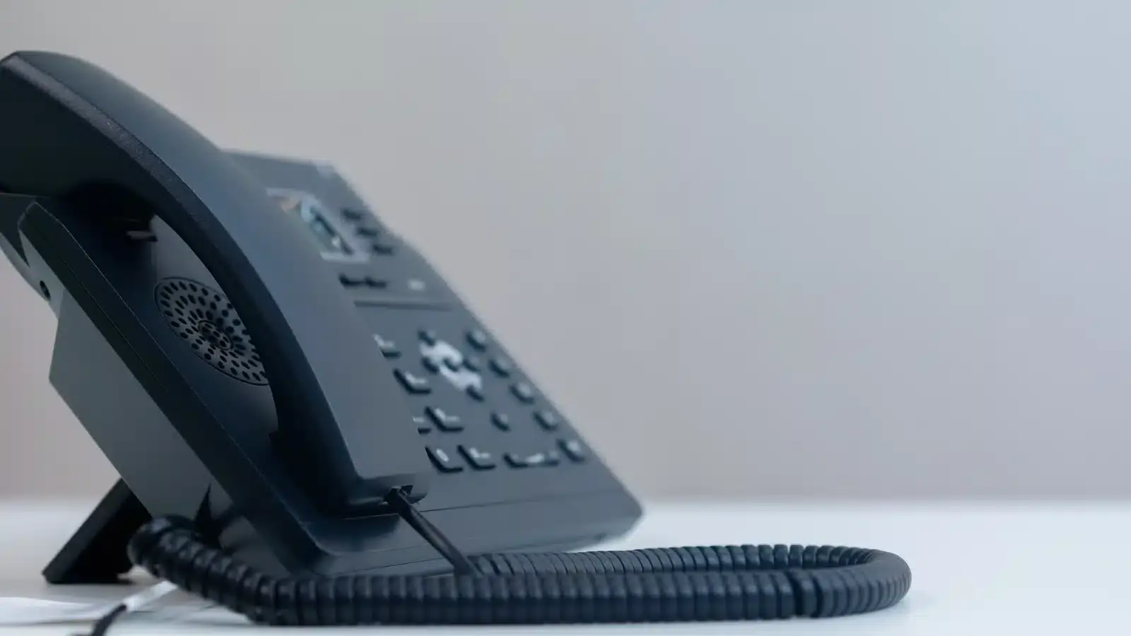 A desk telephone on a clinic front desk with open space beside it, representing the phone enquiries that form-only tracking never records.