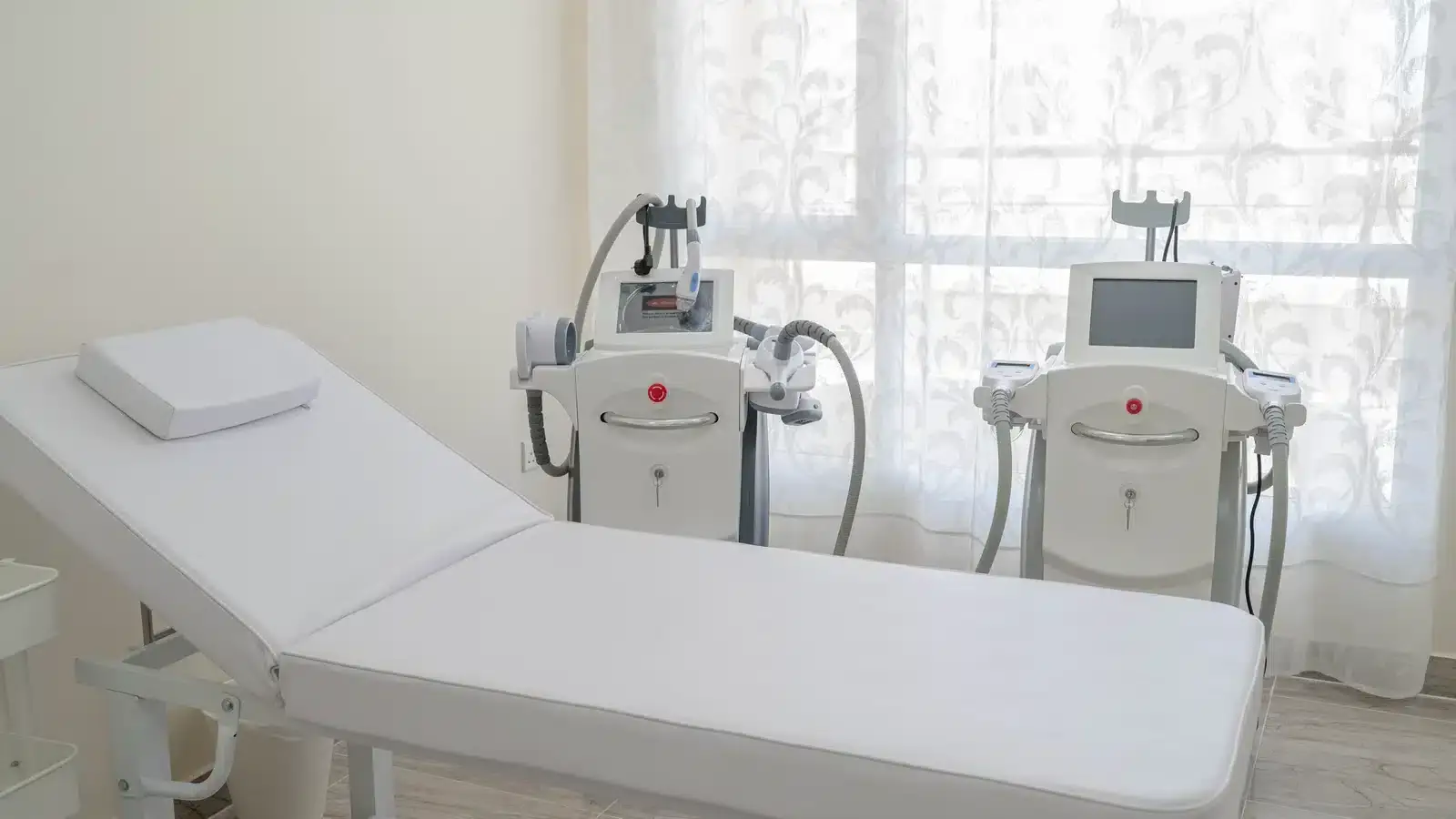 A treatment bed beside two body-contouring devices in an aesthetic clinic room, illustrating why each treatment a med spa offers needs its own page.