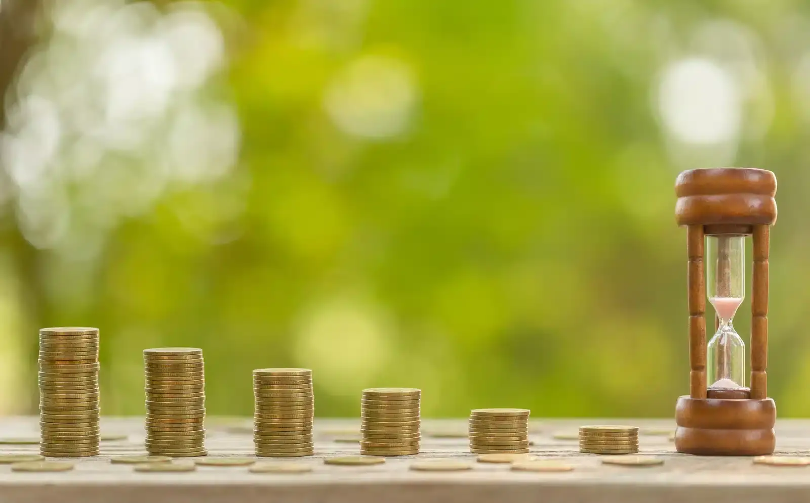 An hourglass beside stacks of coins, illustrating why plastic surgery SEO takes months rather than weeks.