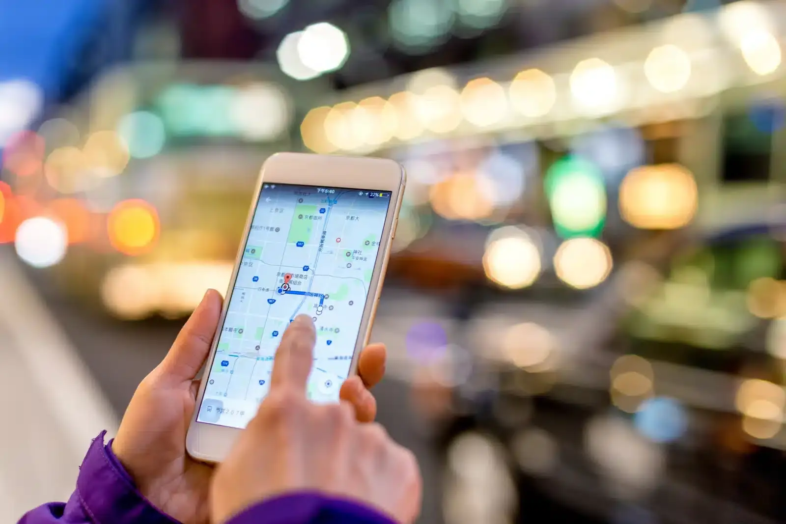 A hand holding a smartphone showing a map, illustrating how patients use local search to find a plastic surgeon nearby.
