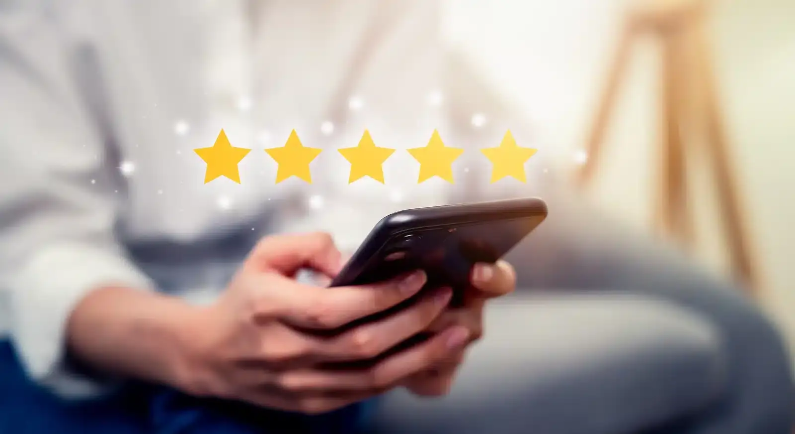 A person holding a smartphone displaying a five-star rating, illustrating how patient reviews drive local SEO for plastic surgeons.
