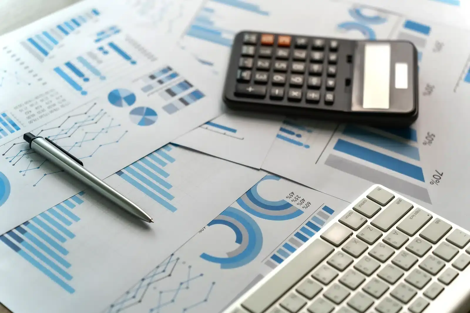 A calculator, pen, and printed budget charts on a desk, illustrating how to plan a plastic surgery SEO budget.