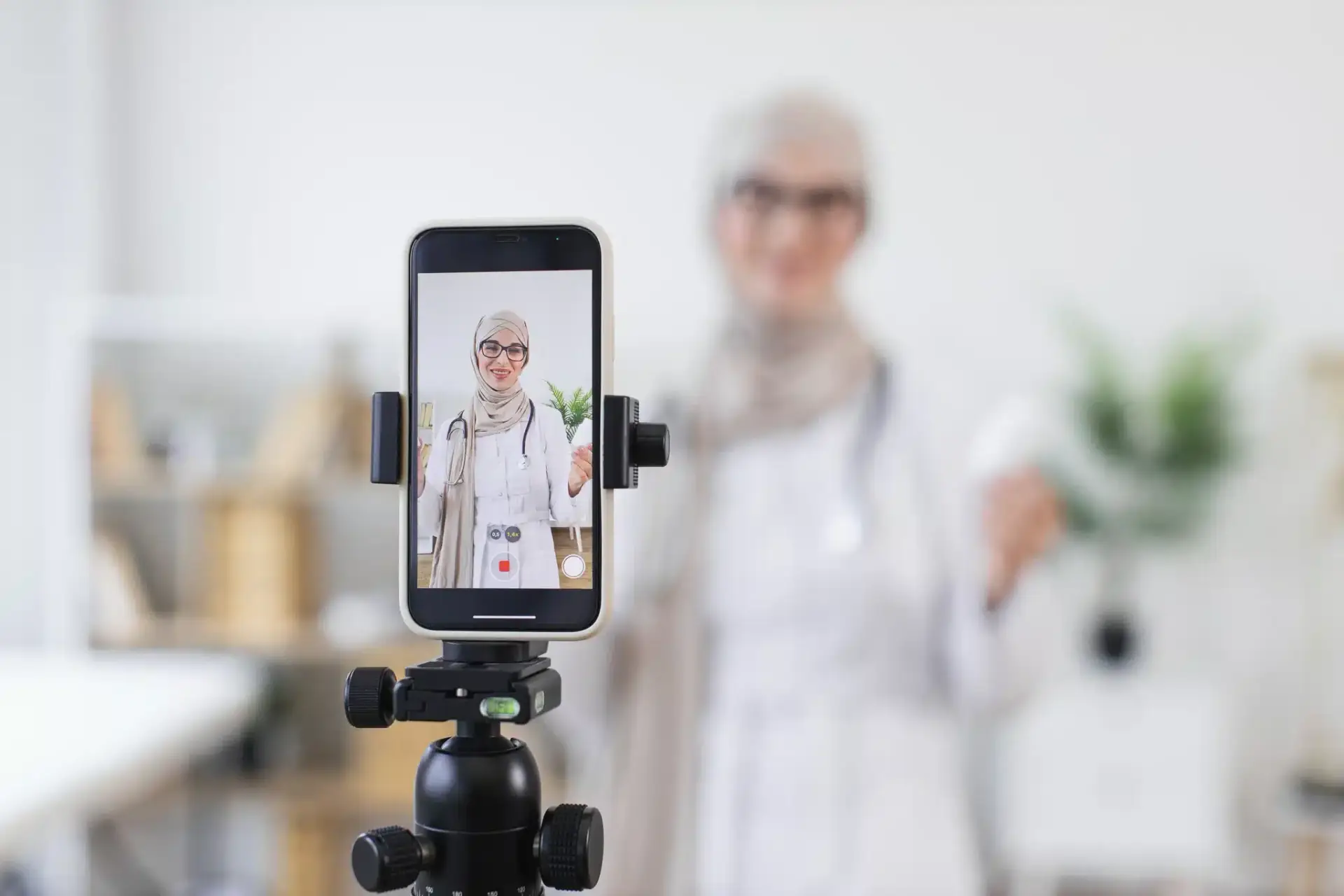 A smartphone on a tripod filming a clinician to produce short-form social media video for a plastic surgery practice
