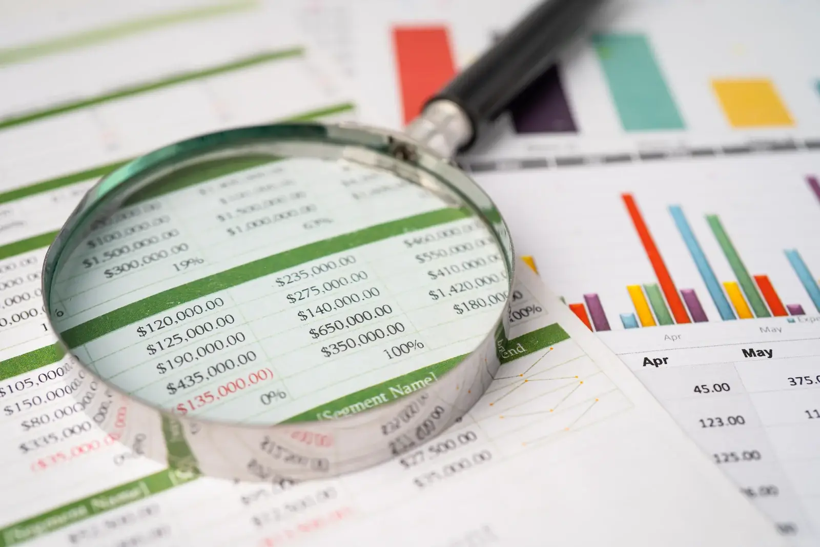 A magnifying glass examining data reports, illustrating how to diagnose why a plastic surgery website is not ranking.